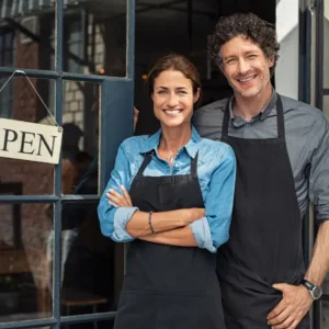Local entrepreneurs stand proudly outside their startup, welcoming customers with an ‘OPEN’ sign.