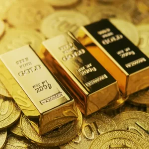 Shiny gold bars stacked atop a pile of embossed gold coins. Visual for a Guide to Gold Trading, highlighting purity, value, and the allure of precious metals.