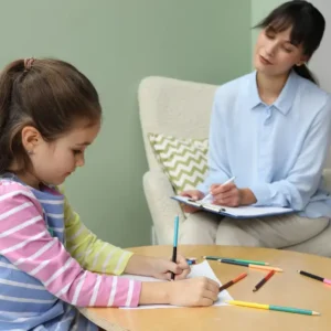Child psychology and mental health course level 3 – young girl engaged in creative therapy with adult observer in calm educational setting